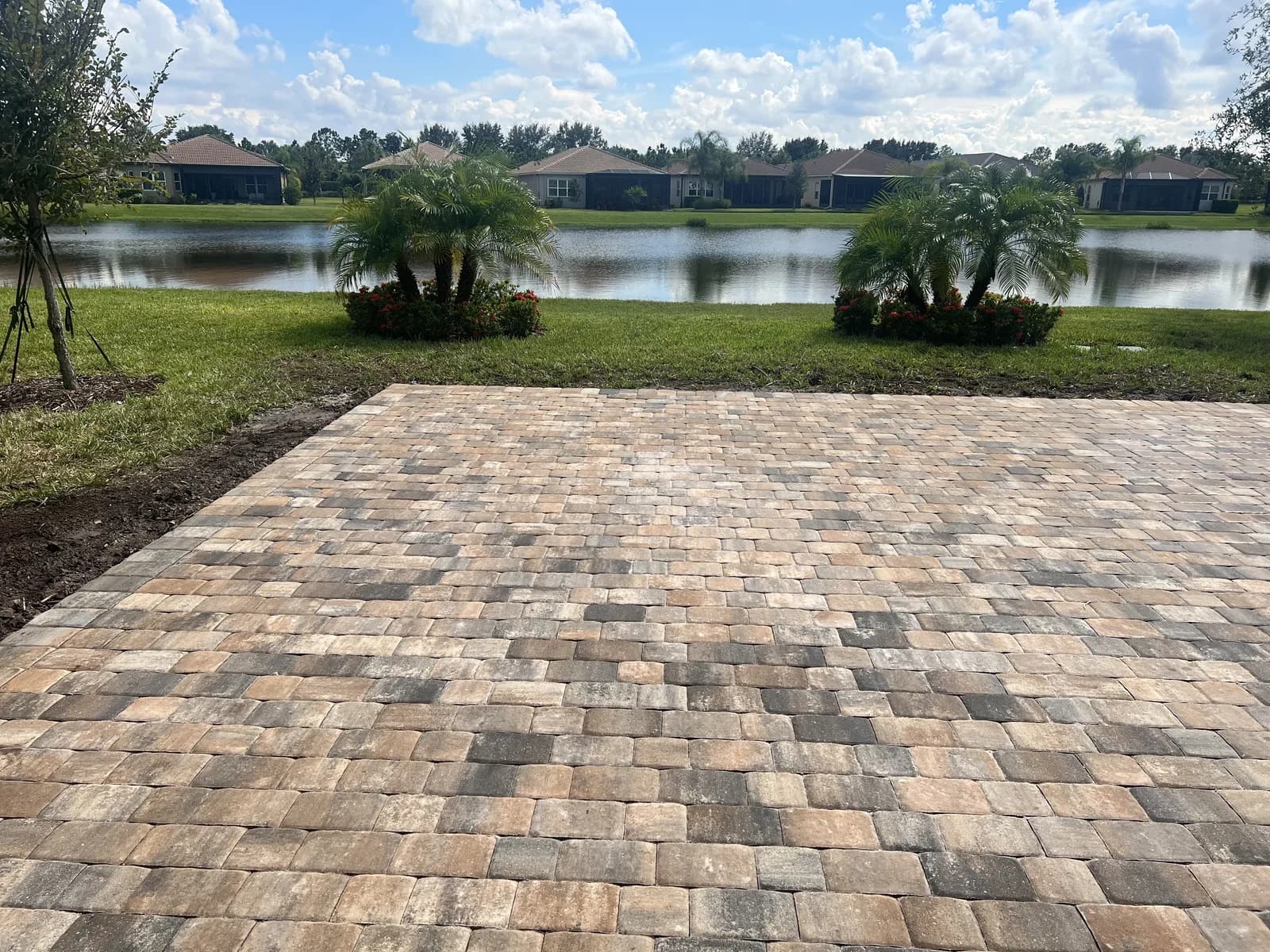 Tumbled brick paver patio overlooking a lake with palm trees