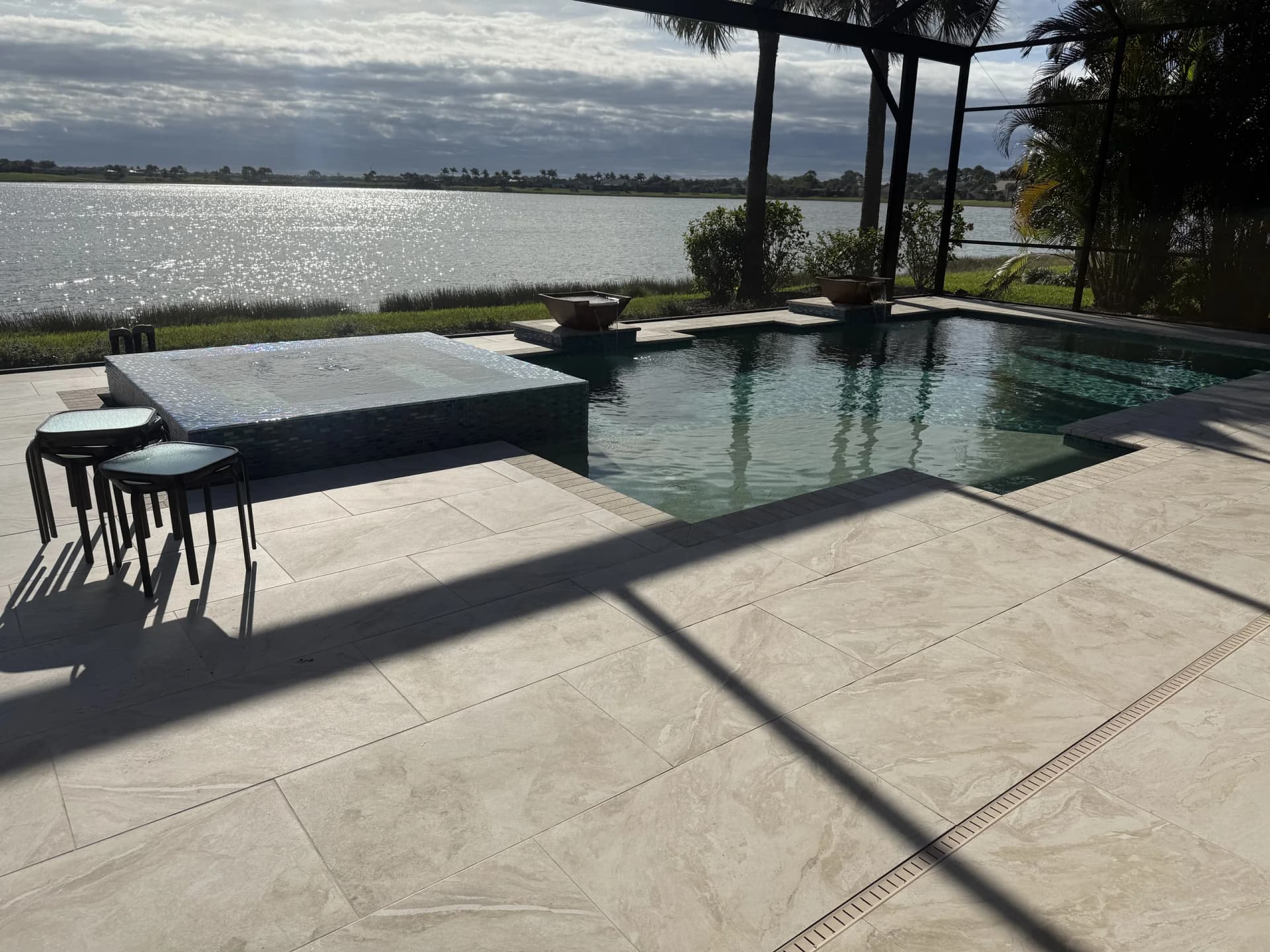 Screened lanai with infinity-edge pool and paver deck overlooking a lake in Florida