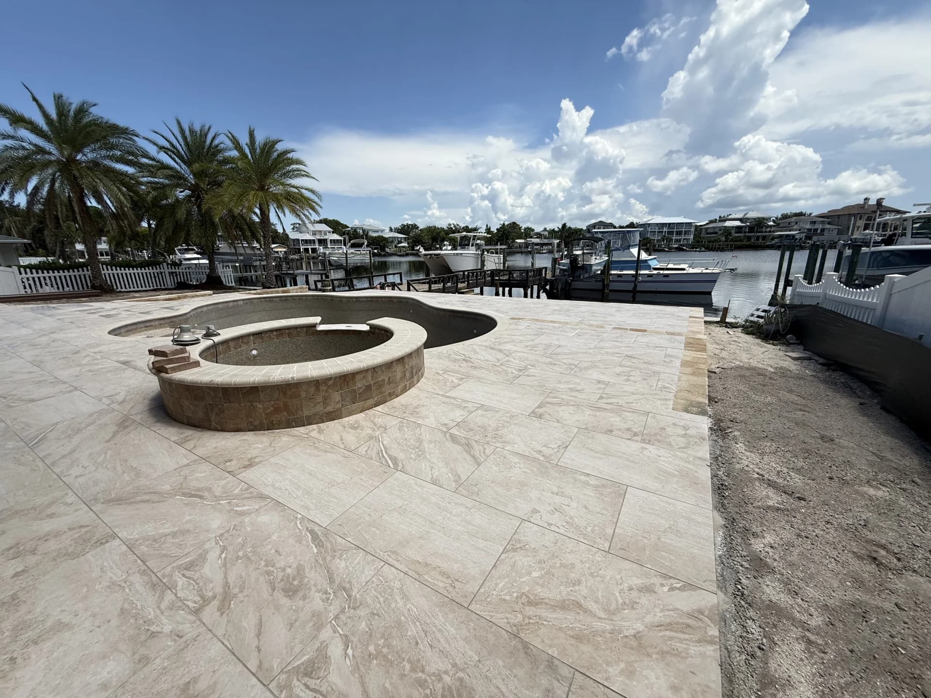 Paver pool deck with round fire pit overlooking a private dock and marina