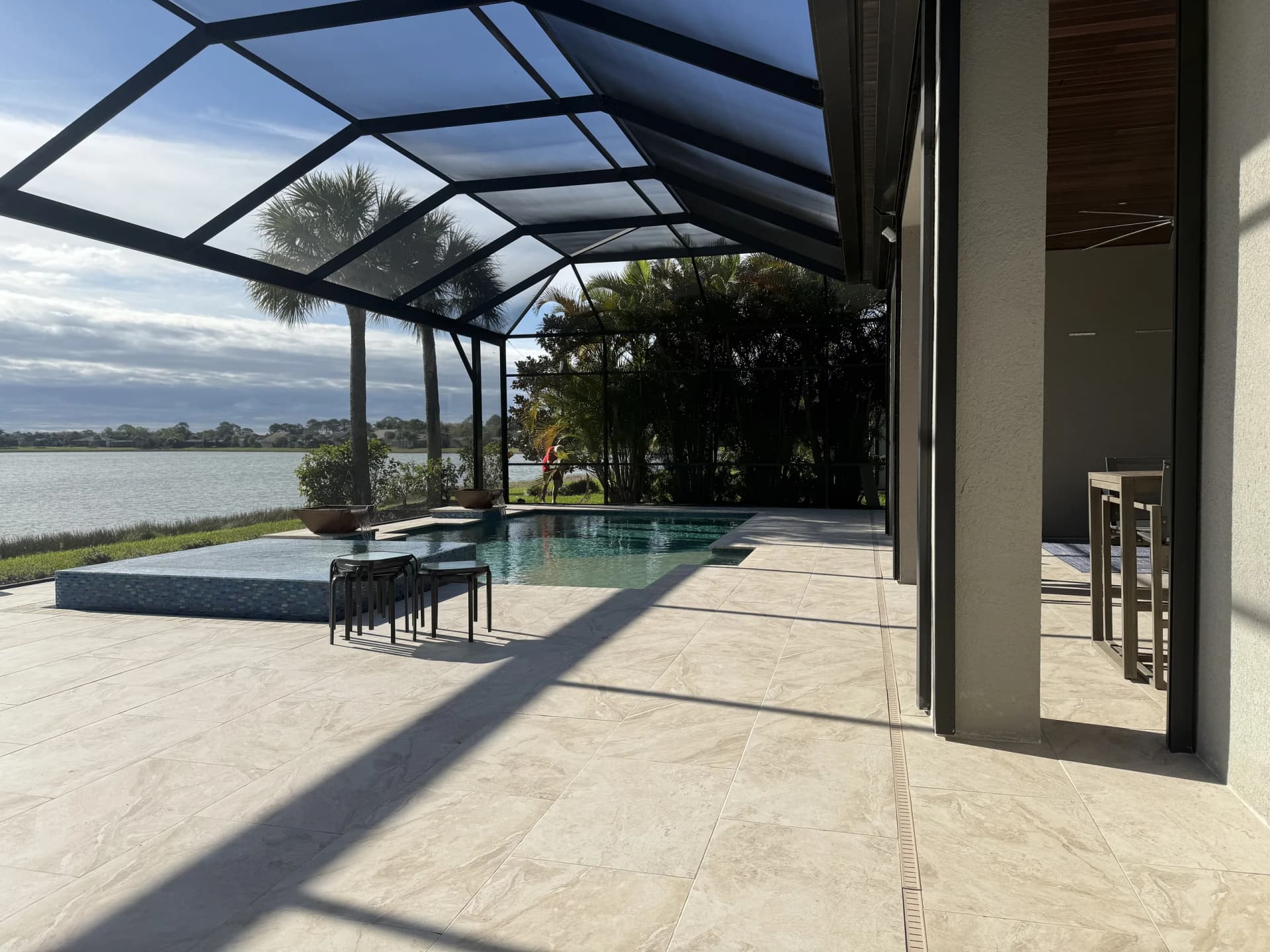 Wide screened lanai and paver pool deck facing a lake in Florida
