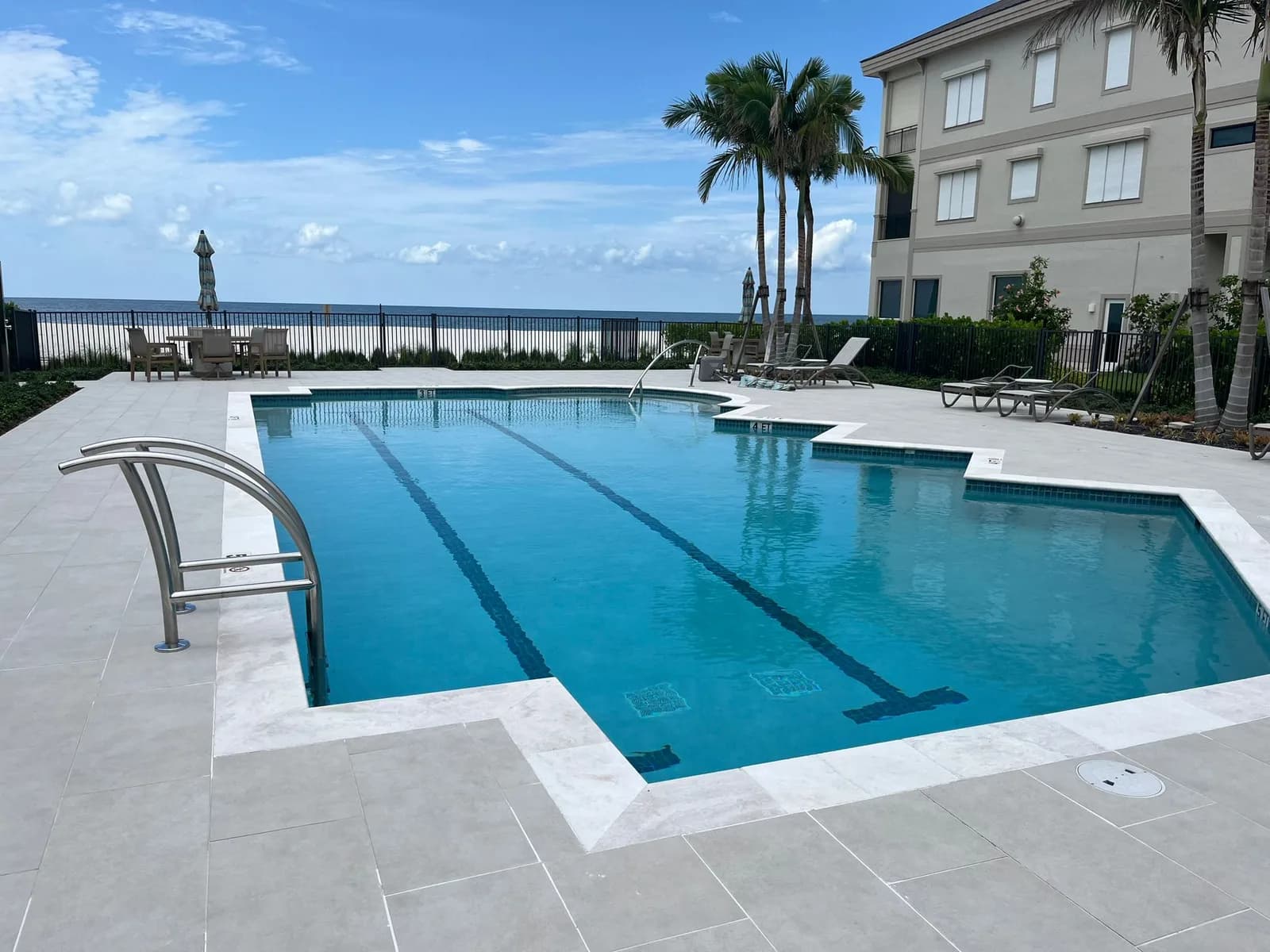 Beachfront lap pool with natural stone paver deck and lounge area
