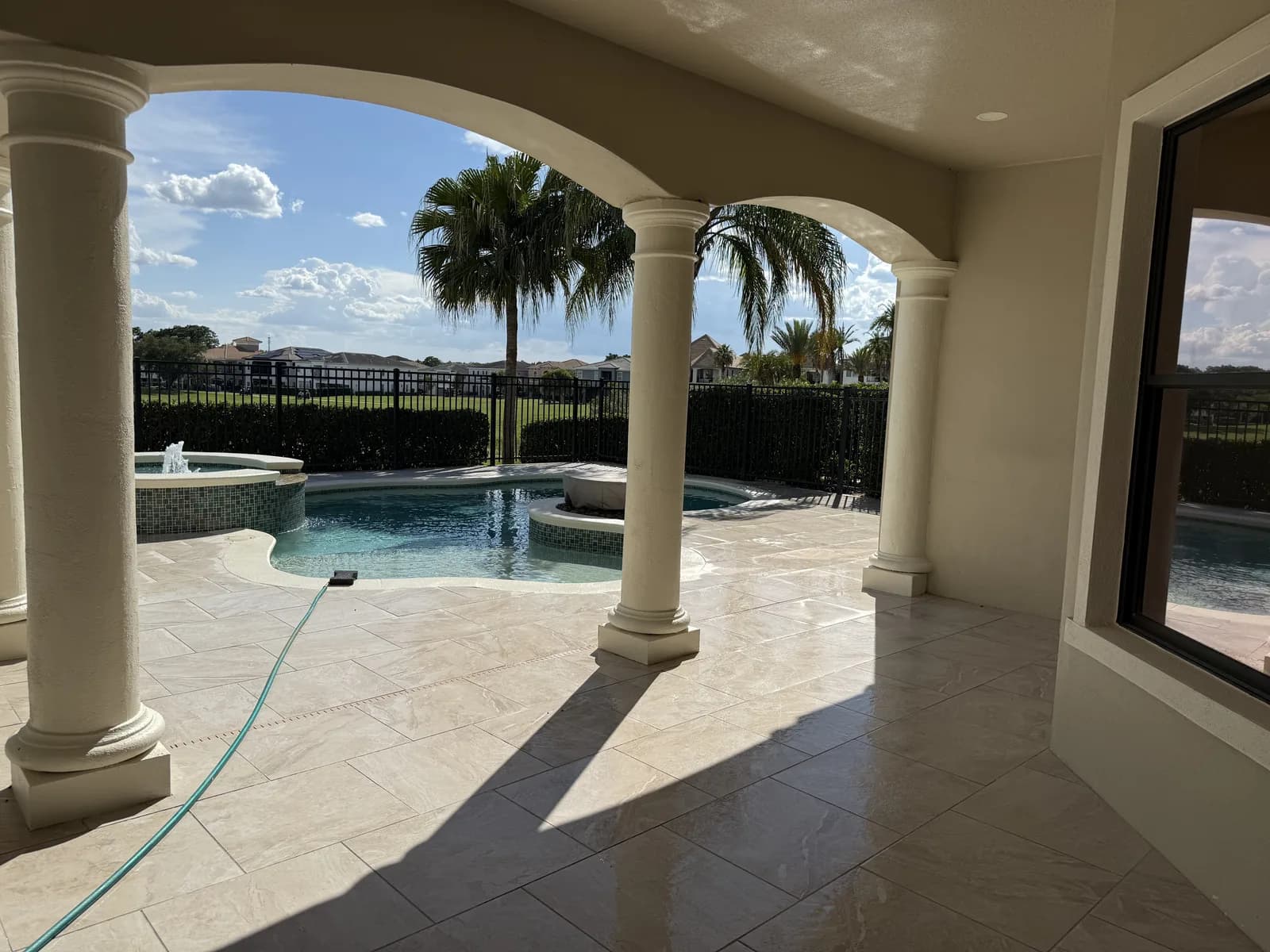 Arched lanai opening onto a paver patio with pool and spa
