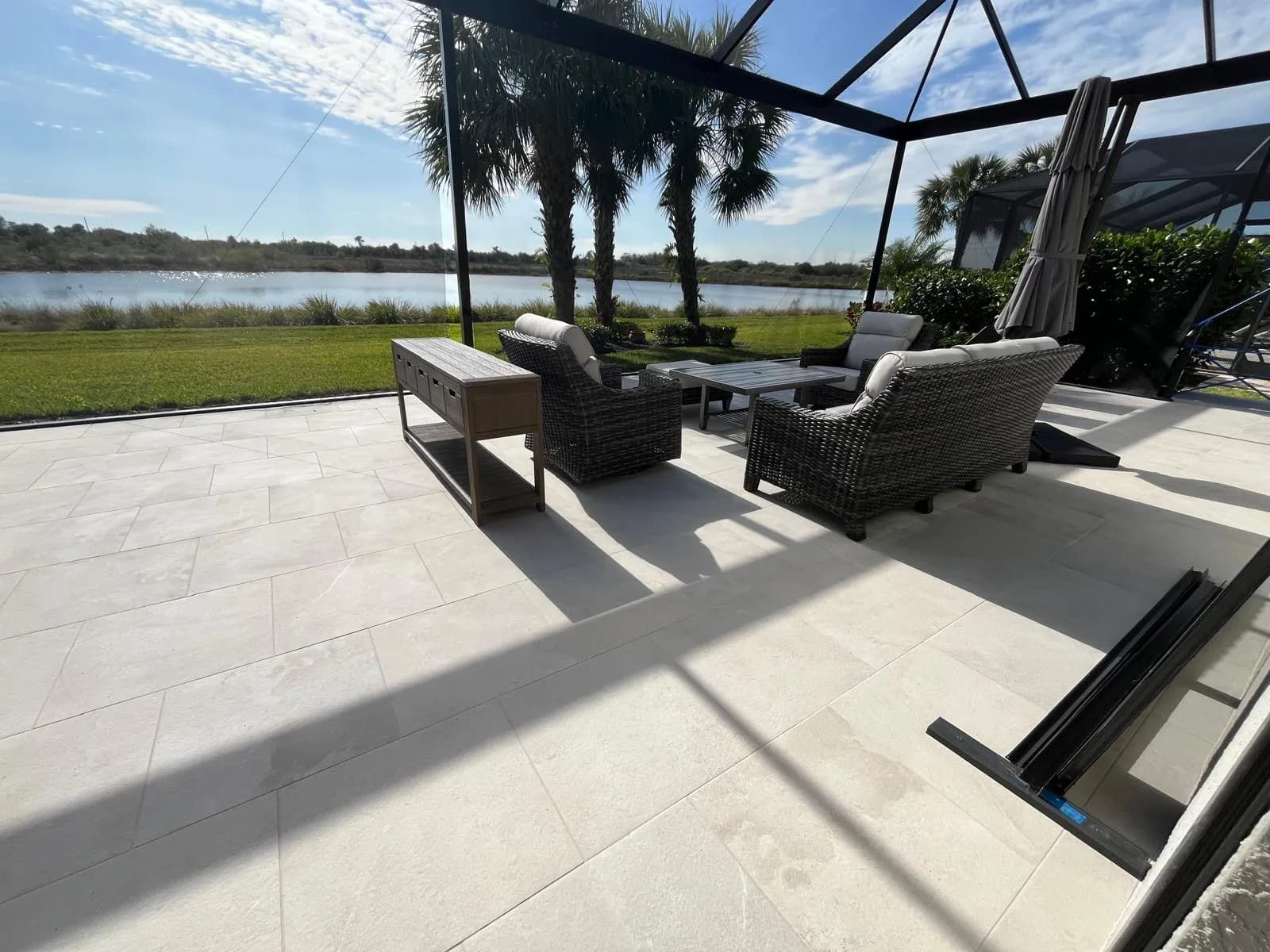 Lakefront paver patio with lounge seating framed by palm trees