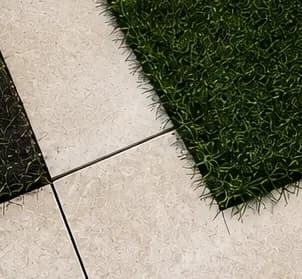 Poorly cut porcelain paver leaving a gap at the turf edge, a sign of rushed installation