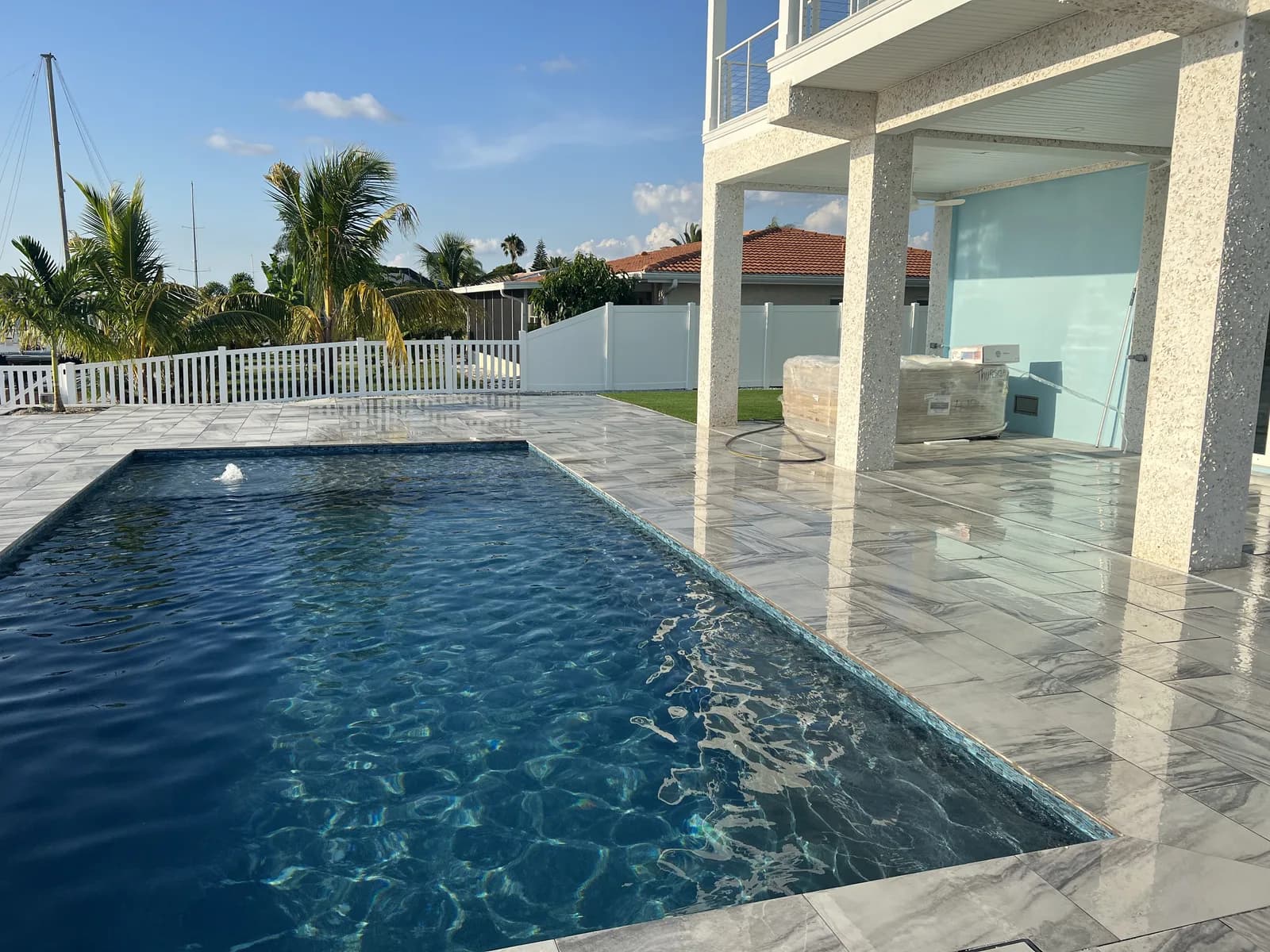 Infinity-edge pool with porcelain paver deck on a canal-front lot