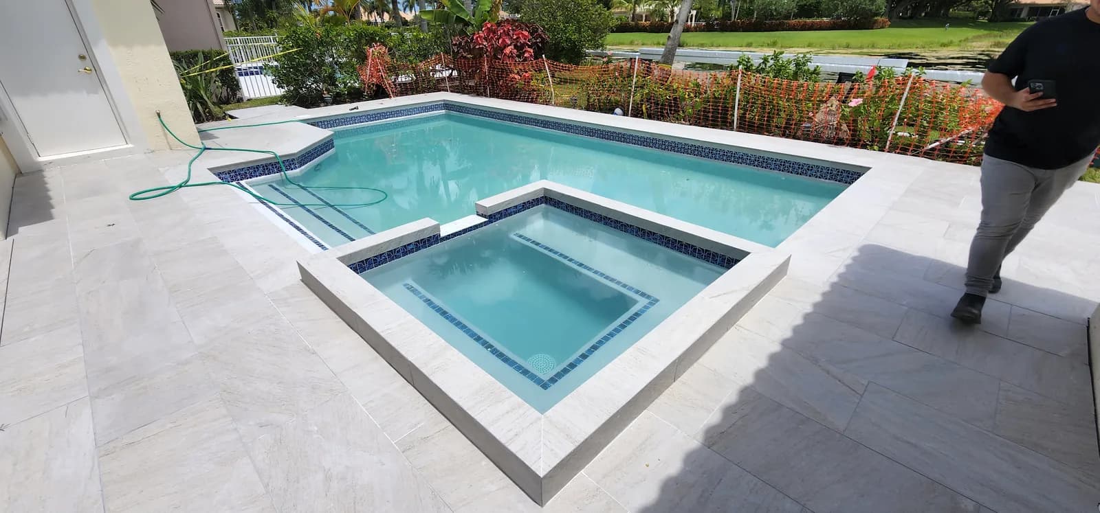 Geometric pool and spa with porcelain paver surround and turf border