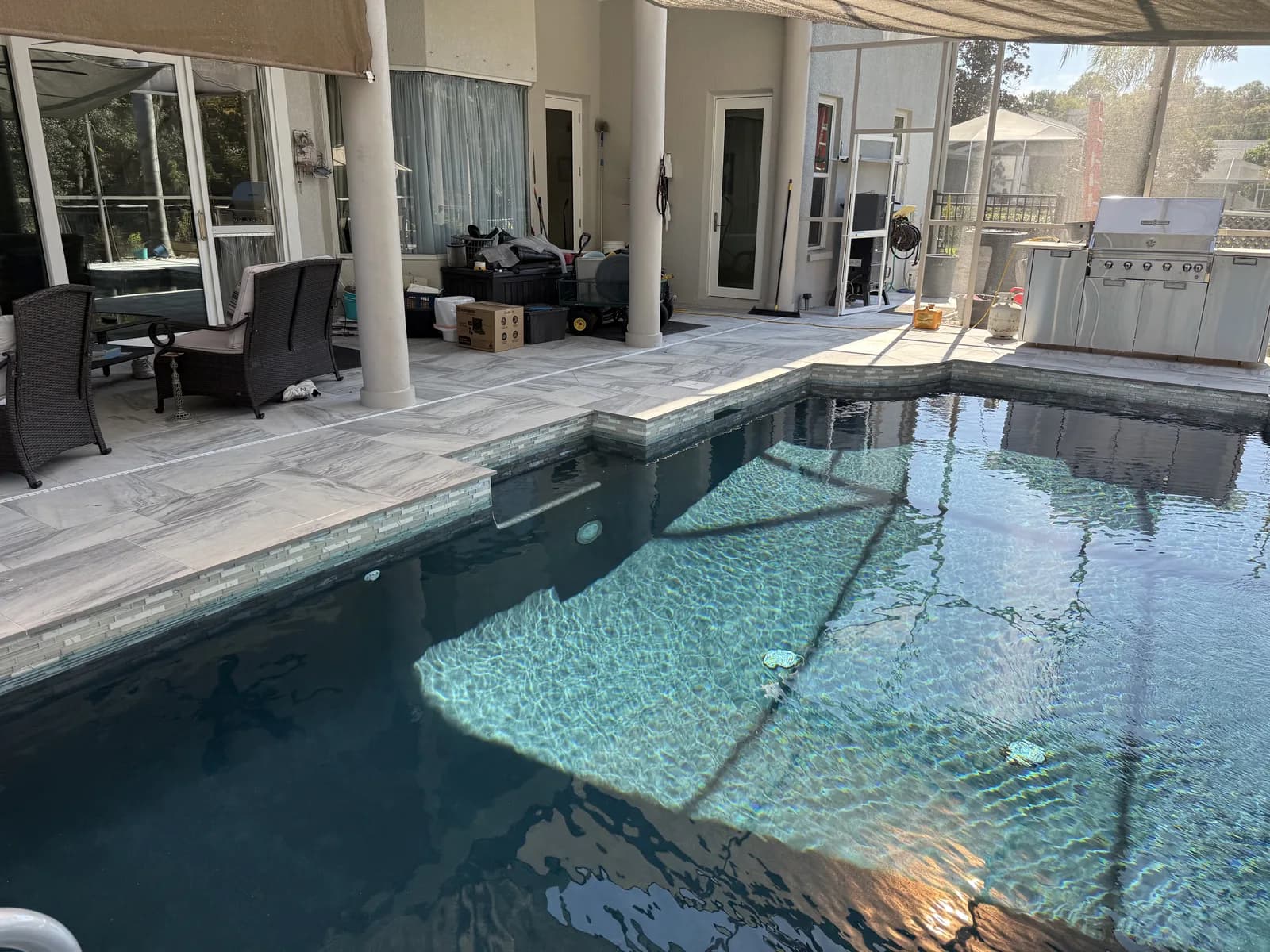 Large-format porcelain paver deck inside a screened pool enclosure