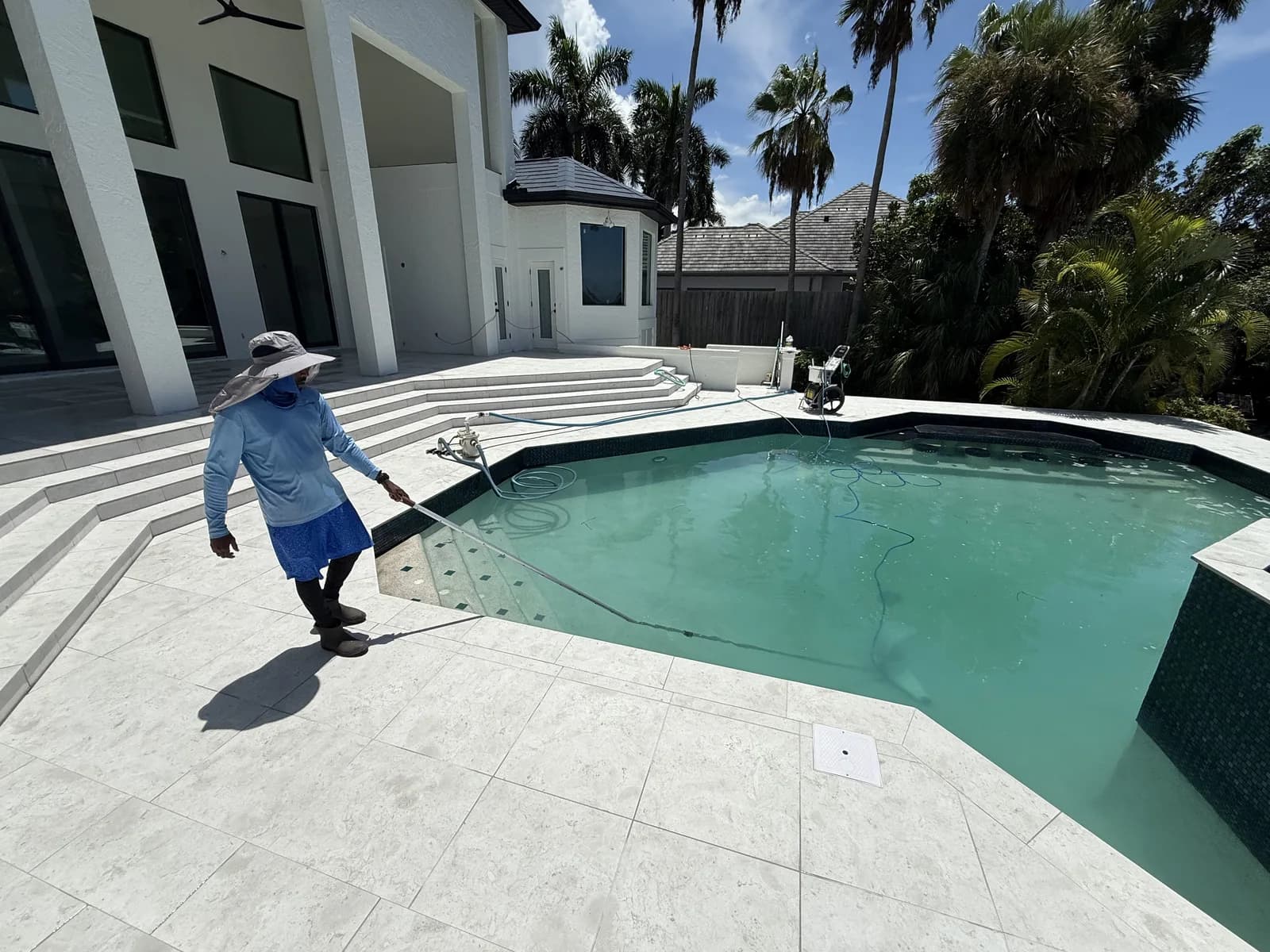 EC Paver Solutions crew assessing and cleaning a travertine pool deck before repair