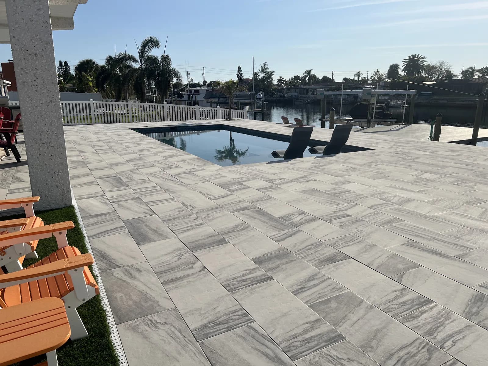 Herringbone travertine paver deck with Adirondack chairs on a waterfront lot