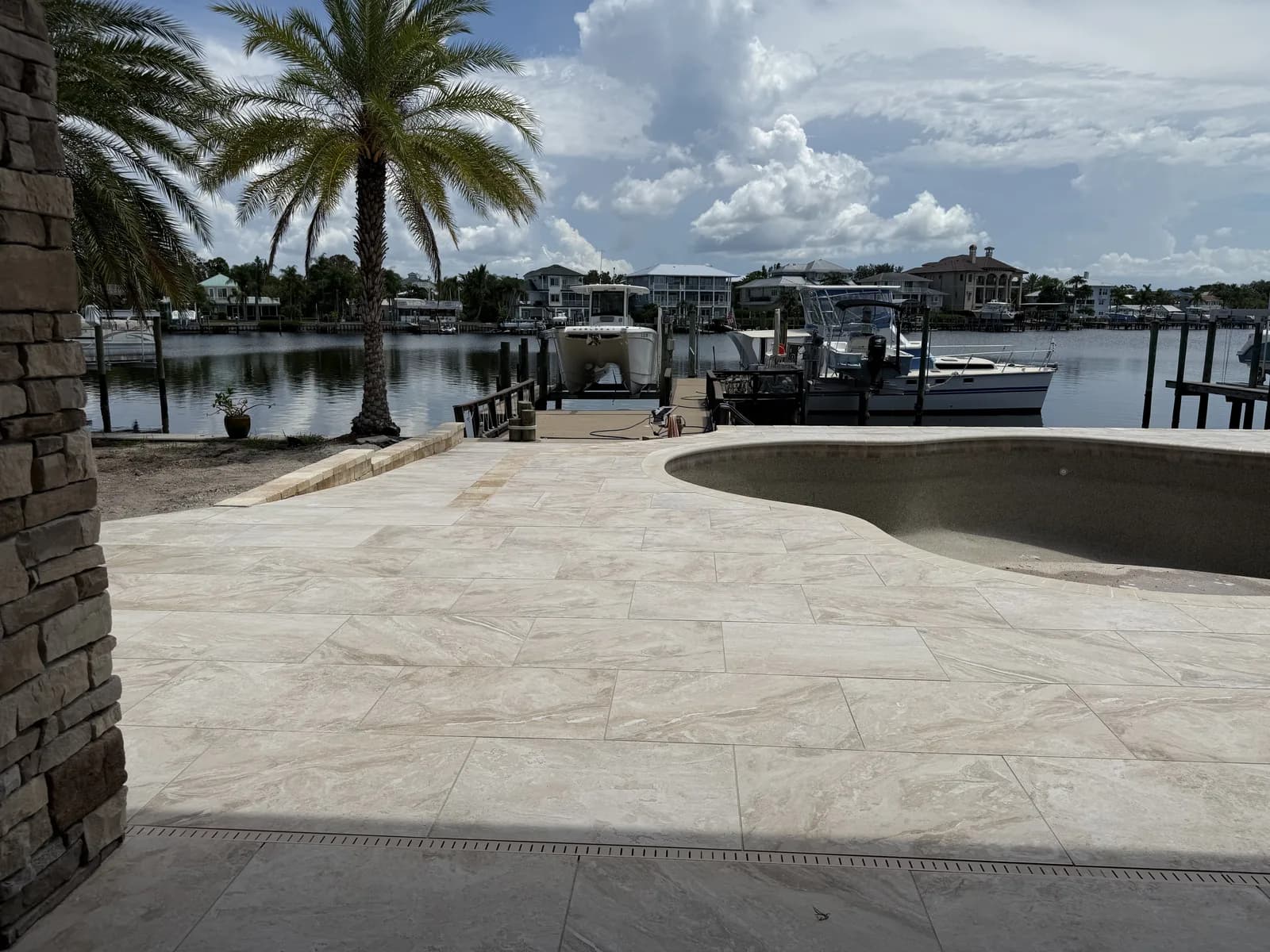 Round spa set into a travertine paver deck overlooking a marina