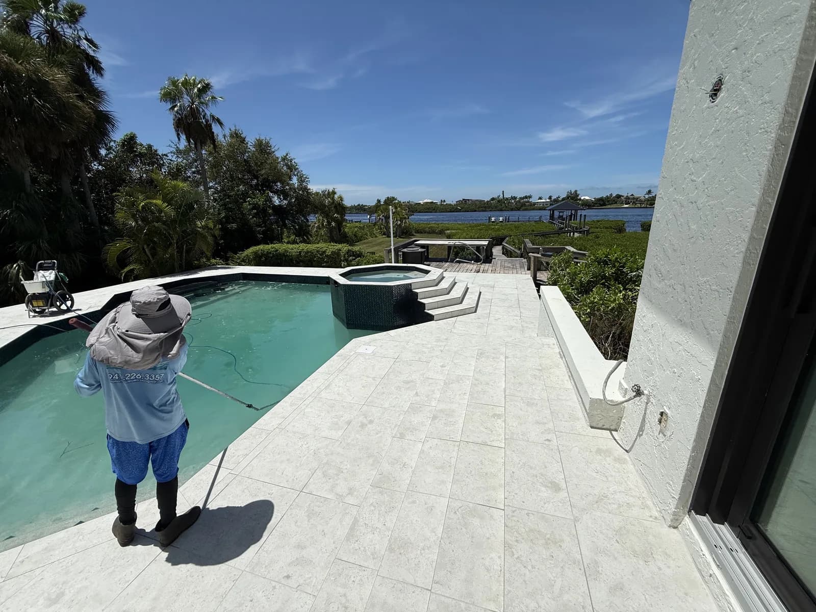 EC Paver Solutions crew sealing a travertine pool deck at a waterfront home