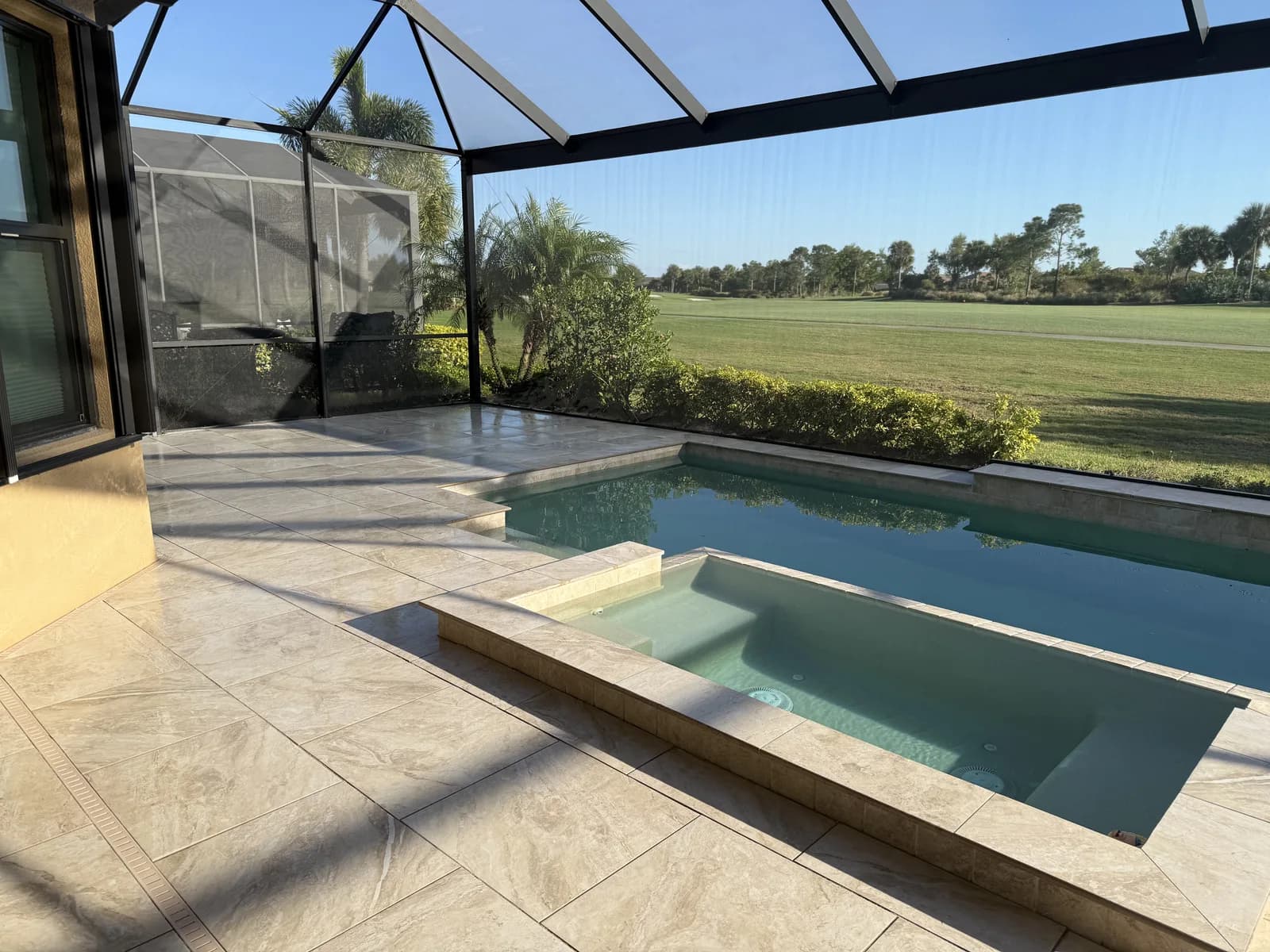 Travertine pool deck and spa with golf course views in Florida