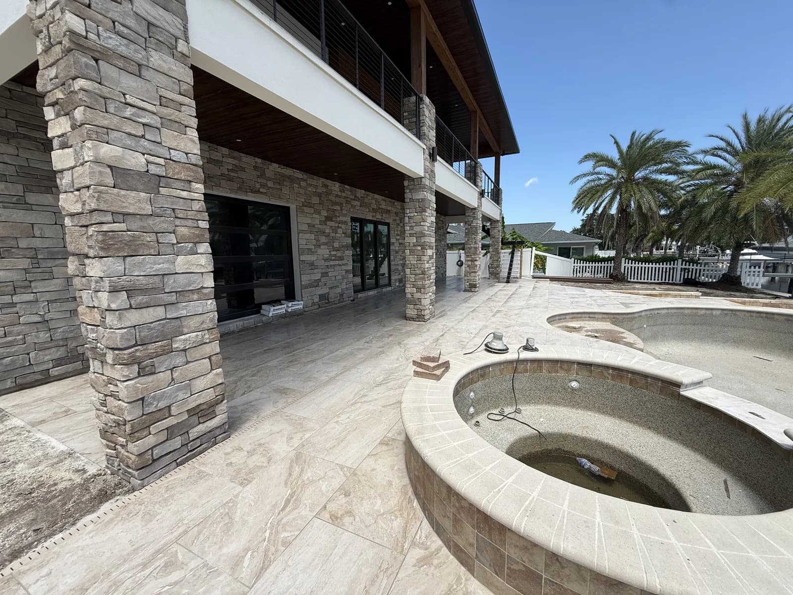 Travertine pool deck with stacked stone column and raised spa overlooking palms