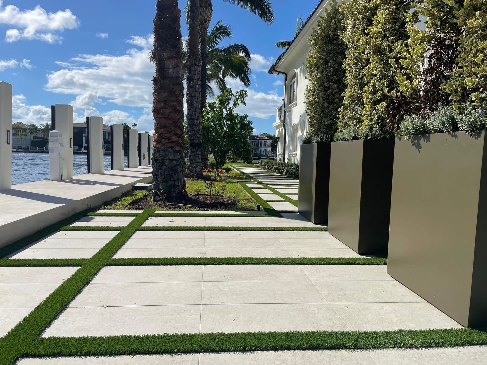 Paver and turf walkway running through a palm-lined courtyard